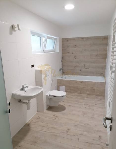 Rodinný dom v obci Bernolákovo, po kompletnej rekonštrukcii - Kúpeľňa v rodinnom dome s podlahou s dreveným dekorom, vaňou a umývadlom.