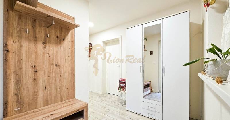 Rodinný dom v obci Bernolákovo, po kompletnej rekonštrukcii - Predsieň v rodinnom dome so skriňou, vešiakom a podlahou s dreveným dekorom.