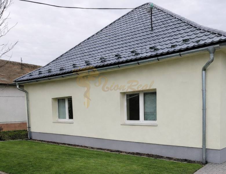 Rodinný dom v obci Bernolákovo, po kompletnej rekonštrukcii - Rodinný dom v Bernolákove s trávnikom, šedou strechou a svetlou fasádou.