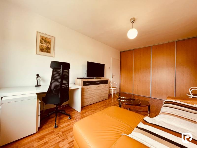 EXKLUZÍVNE! | Krásny 2-izbový byt | 52m² | Považanova - Izba v 2-izbovom byte s podlahou s dreveným dekorom, písacím stolom a sedačkou.