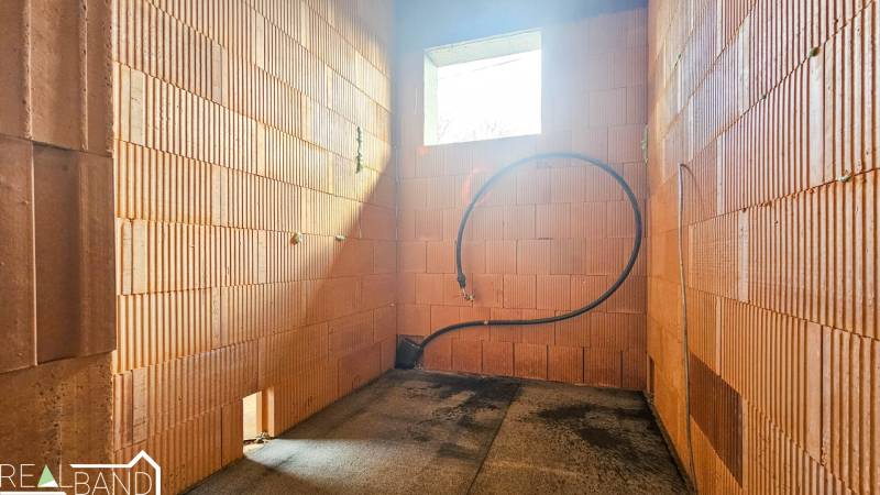 PRIESTRANNÁ 4-IZBOVÁ NOVOSTAVBA 167.38m²- BUNGALOV NA POZEMKU AŽ 702m² - Nedokončený interiér v rodinnom dome s pohľadovým murivom a otvorom pre okno.