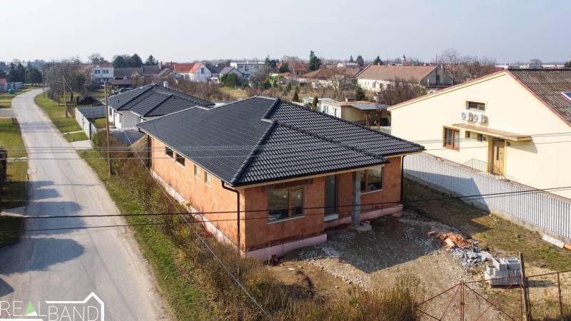 PRIESTRANNÁ 4-IZBOVÁ NOVOSTAVBA 167.38m²- BUNGALOV NA POZEMKU AŽ 702m² - Rodinný dom v Pavliciach vo fáze výstavby so šikmou strechou a tehlovou fasádou.