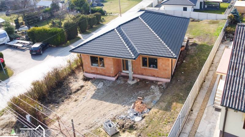 PRIESTRANNÁ 4-IZBOVÁ NOVOSTAVBA 167.38m²- BUNGALOV NA POZEMKU AŽ 702m² - Stavebný rodinný dom v meste Pavlice so strechou z tmavých škridiel.