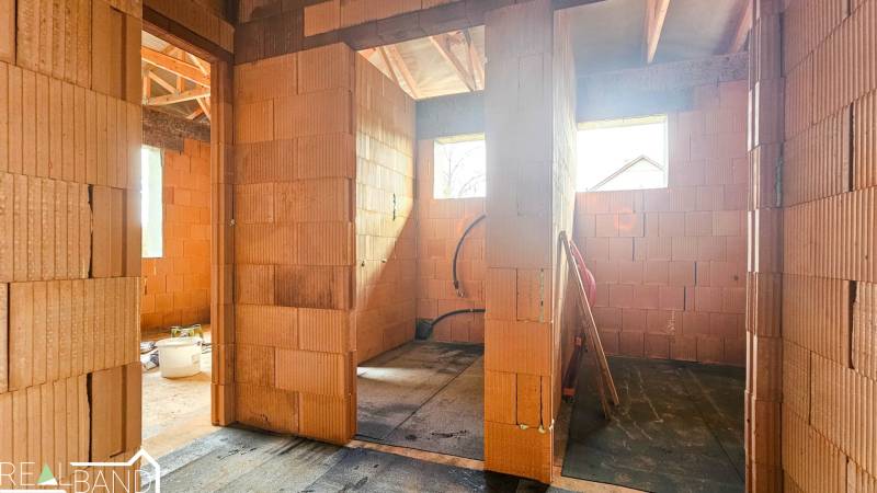 PRIESTRANNÁ 4-IZBOVÁ NOVOSTAVBA 167.38m²- BUNGALOV NA POZEMKU AŽ 702m² - Interiér rozostavaného rodinného domu s tehlovými priečkami a strešnými nosníkmi.
