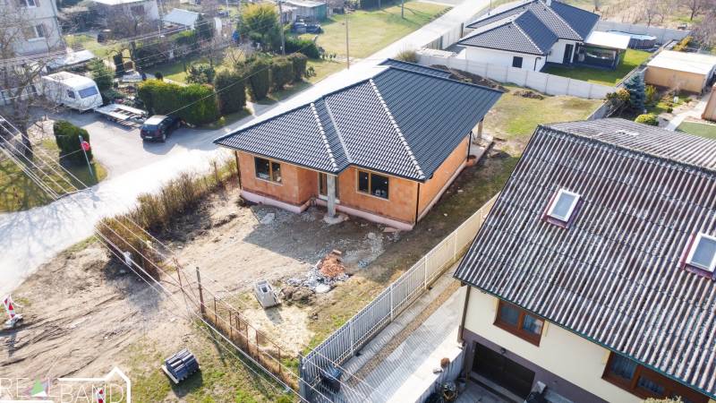 PRIESTRANNÁ 4-IZBOVÁ NOVOSTAVBA 167.38m²- BUNGALOV NA POZEMKU AŽ 702m² - Rodinný dom v Pavliciach, súčasť obytnej štvrti, s plechovou strechou a nedokončeným okolím.