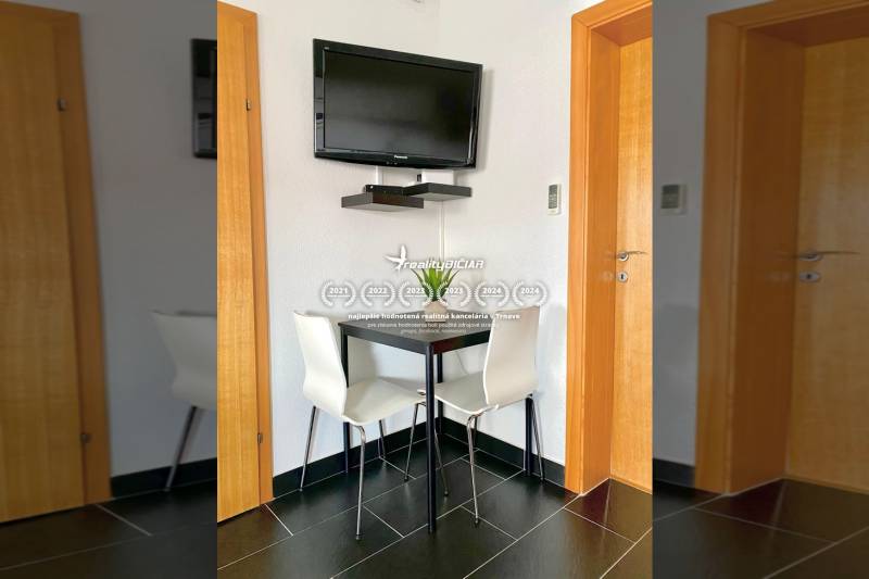 NIN-GRBLJANSKE VIKENDICE - dom s dvoma bytmi - Jedáleň v rodinnom dome s rohovým stolom, televízorom na stene a čiernymi dlaždicami.