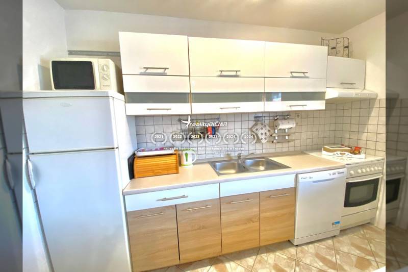 NIN-GRBLJANSKE VIKENDICE - dom s dvoma bytmi - Kuchyňa v Rodinnom dome s bielymi skrinkami, sporákom a mikrovlnkou.