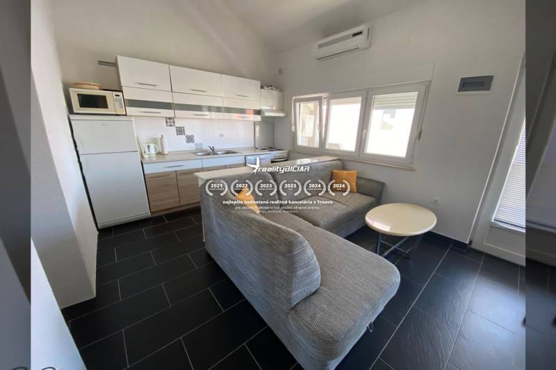 NIN-GRBLJANSKE VIKENDICE - dom s dvoma bytmi - Kuchyňa s rohovým gaučom a jedálenským stolíkom, rodinný dom, podlaha s tmavým obkladom.