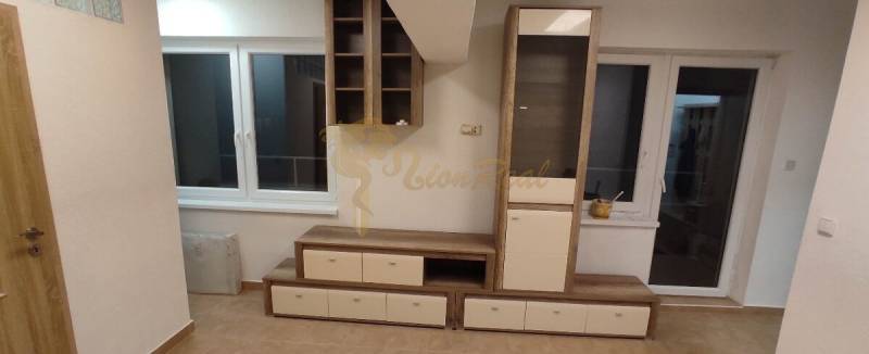 1-izb. byt, Krížná ul., Staré Mesto s veľkou lodžiou - Obývacia izba v 1-izbovom byte s nábytkom, oknom a podlahou s dreveným dekorom.