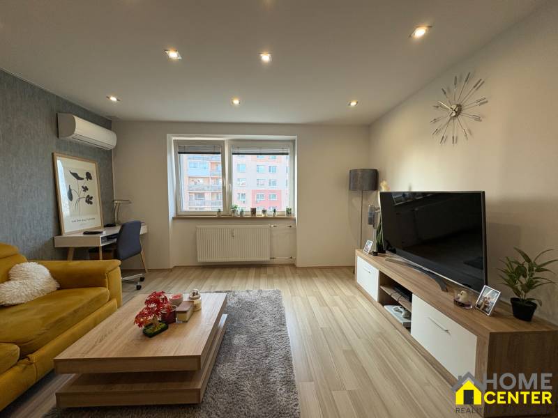 NA PREDAJ vkusne zrekonštruovaný  2 izbový byt, Komárno - Obývacia izba v 2-izbovom byte s podlahou s dreveným dekorom, gaučom a televízorom.