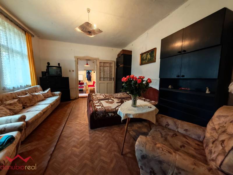 Na predaj rodinný dom v širšom centre mesta Komárno. - Obývacia izba v rodinnom dome s pohovkami, TV a podlahou s dreveným dekorom.