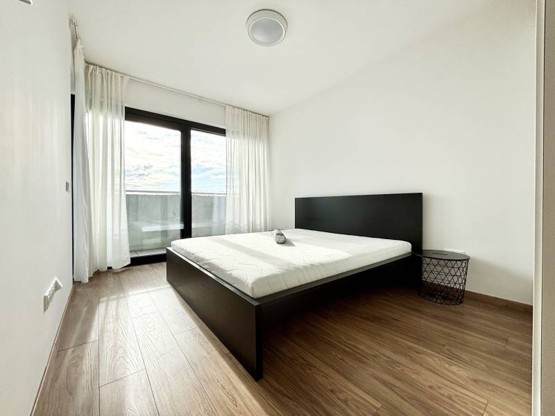 I PRENÁJOM - Nový moderný 2-izb. byt, TEHELNÉ POLE, Bajkalská - Spálňa v 2-izbovom byte na ulici Bajkalská, s posteľou a modernými závesmi.