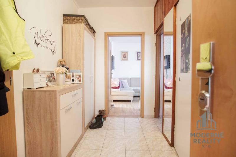 3-izbový byt s loggiou na ul. S.H. Vajanského, Nové Zámky – 74,69m2 - Chodba v 3-izbovom byte s dlažbou a útulným nábytkom v drevenom dekore.