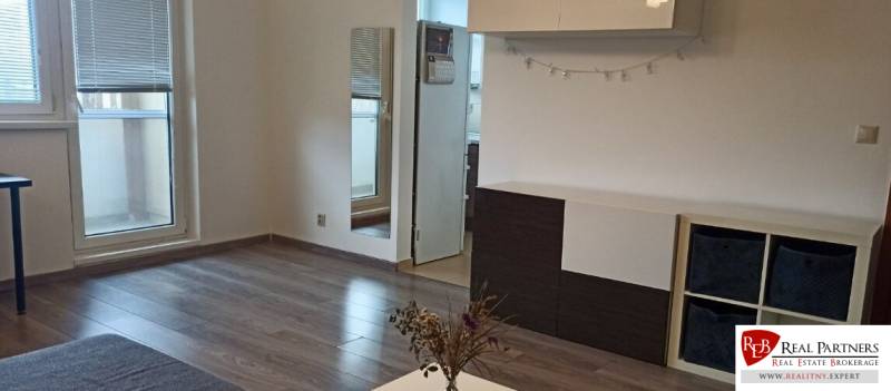 Prenájom 2-izbový byt na začiatku Petržalky - Obývačka v 2-izbovom byte s podlahou s dreveným dekorom a nábytkom.