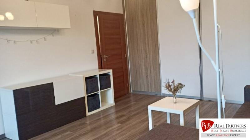 Prenájom 2-izbový byt na začiatku Petržalky - Obývacia izba v 2-izbovom byte s podlahou s dreveným dekorom a moderným nábytkom.