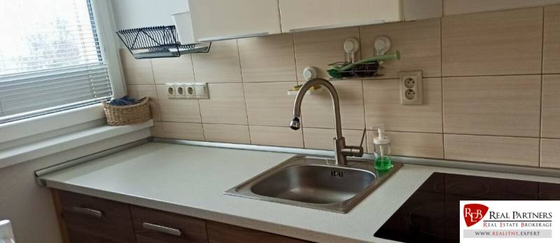 Prenájom 2-izbový byt na začiatku Petržalky - Kuchyňa v 2-izbovom byte s umývadlom, sklokeramickou varnou doskou a košíkom pri okne.