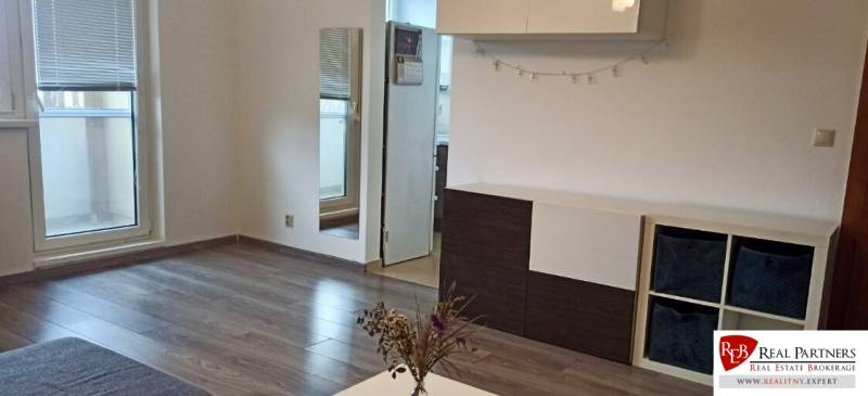 Prenájom 2-izbový byt na začiatku Petržalky - Obývacia izba v 2-izbovom byte s podlahou s dreveným dekorom a vstupom na balkón.