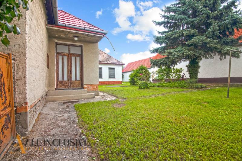 NA PREDAJ 2 ROD. DOMY NA 12-ÁROVOM POZEMKU, MALÁ MAČA - Rodinný dom na Malej Mači v Galante s červenou strechou a zelenou záhradou.