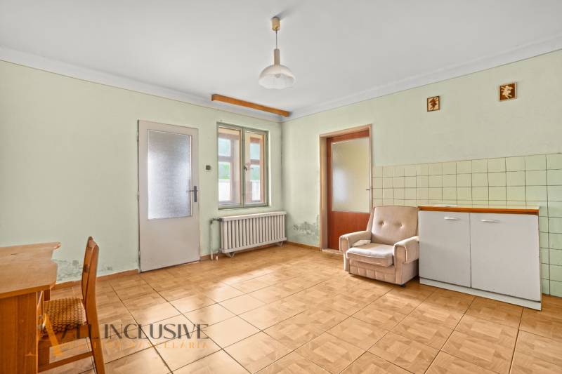 NA PREDAJ 3-IZBOVÝ RODINNÝ DOM, PUSTÉ ÚĽANY - Obývacia izba v rodinnom dome s podlahou s dreveným dekorom a jednoduchým nábytkom.