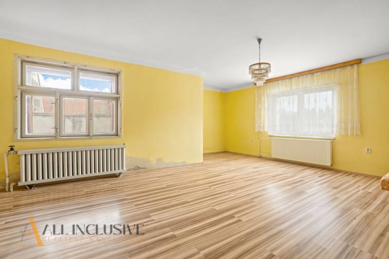 NA PREDAJ 3-IZBOVÝ RODINNÝ DOM, PUSTÉ ÚĽANY - Obývacia izba s podlahou s dreveným dekorom, žltými stenami a lustrom v rodinnom dome.