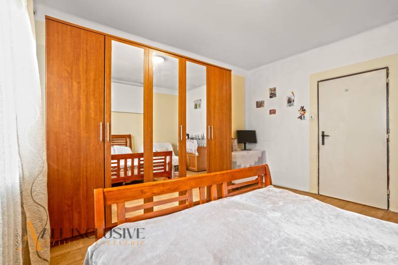 NA PREDAJ 5-IZBOVÝ RODINNÝ DOM NA 15Á POZEMKU,ŠALGOČKA - Spálňa v rodinnom dome s drevenou skriňou a zrkadlom, podlaha s dreveným dekorom.