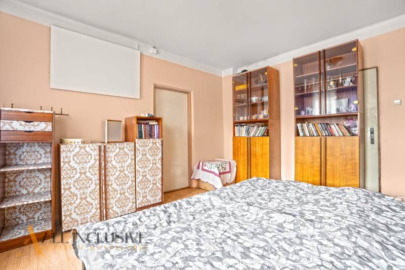 NA PREDAJ 5-IZBOVÝ RODINNÝ DOM NA 15Á POZEMKU,ŠALGOČKA - Interiér rodinného domu s drevodekorovou podlahou, knihovňou a elegantným posteľným pokrytím.