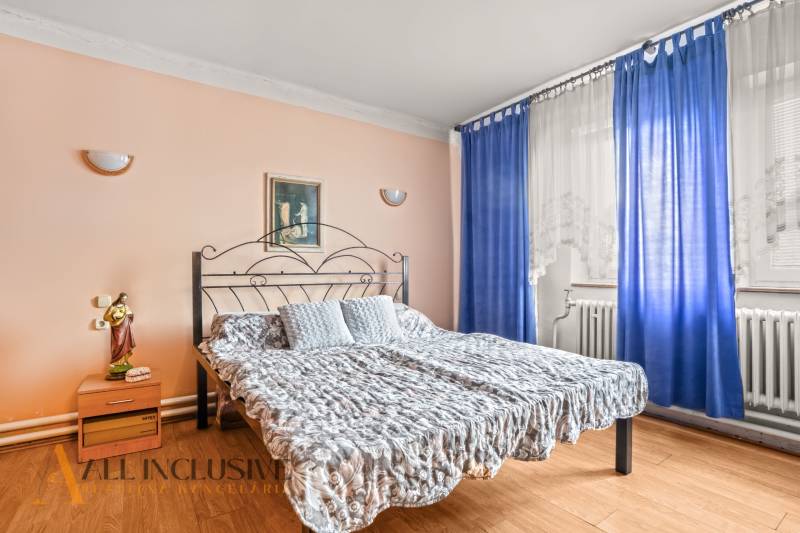 NA PREDAJ 5-IZBOVÝ RODINNÝ DOM NA 15Á POZEMKU,ŠALGOČKA - Spálňa v rodinnom dome s kovovou posteľou, modrými závesmi a podlahou s dreveným dekorom.