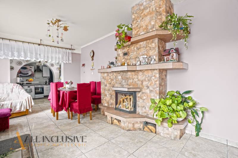 NA PREDAJ 5-IZBOVÝ RODINNÝ DOM NA 15Á POZEMKU,ŠALGOČKA - Obývacia izba v rodinnom dome s krbom, jedálenským stolom a dekoráciami.