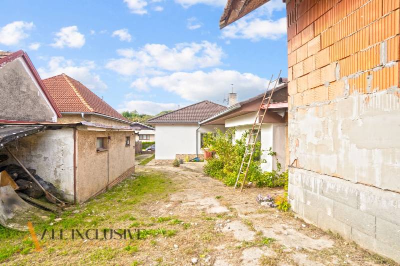 NA PREDAJ 5-IZBOVÝ RODINNÝ DOM NA 15Á POZEMKU,ŠALGOČKA - Rodinný dom v Šalgočke so strechami a neopravenou tehlovou stenou, vedľa je rebrík.