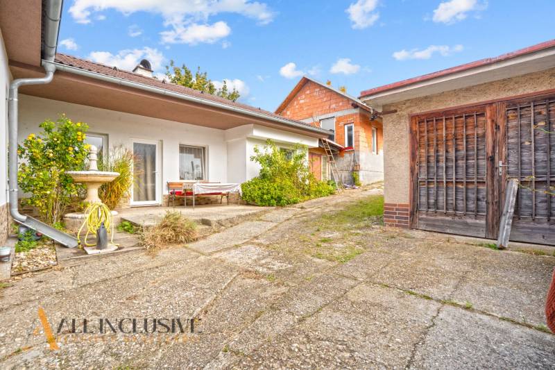 NA PREDAJ 5-IZBOVÝ RODINNÝ DOM NA 15Á POZEMKU,ŠALGOČKA - Dvor rodinného domu v Šalgočke so zeleňou a drevenou garážou.