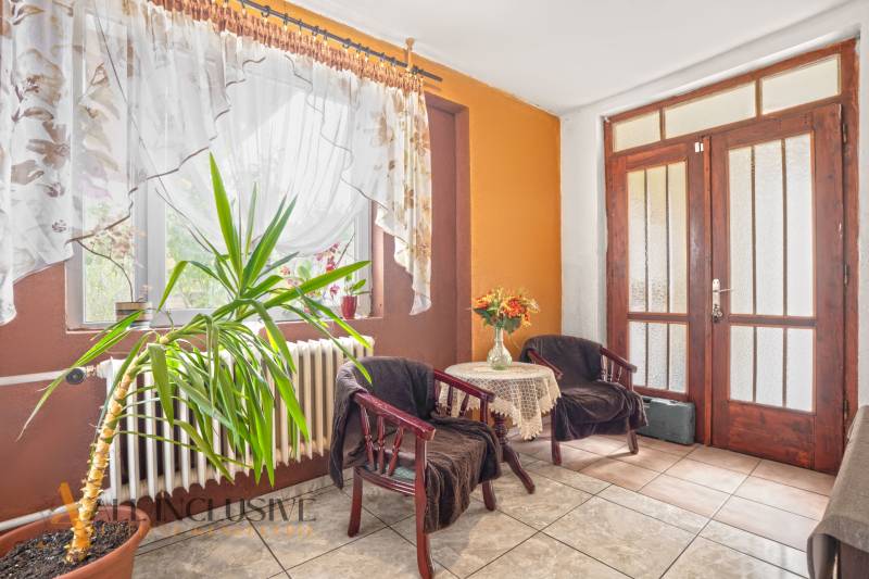 NA PREDAJ 5-IZBOVÝ RODINNÝ DOM NA 15Á POZEMKU,ŠALGOČKA - Interiér rodinného domu s rastlinou, dvoma kreslami a stolíkom s kvetmi.