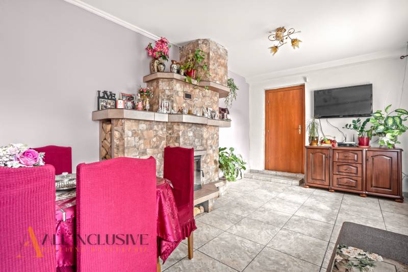 NA PREDAJ 5-IZBOVÝ RODINNÝ DOM NA 15Á POZEMKU,ŠALGOČKA - Obývačka rodinného domu s krbom, kvetmi, červenými stoličkami a dreveným nábytkom.