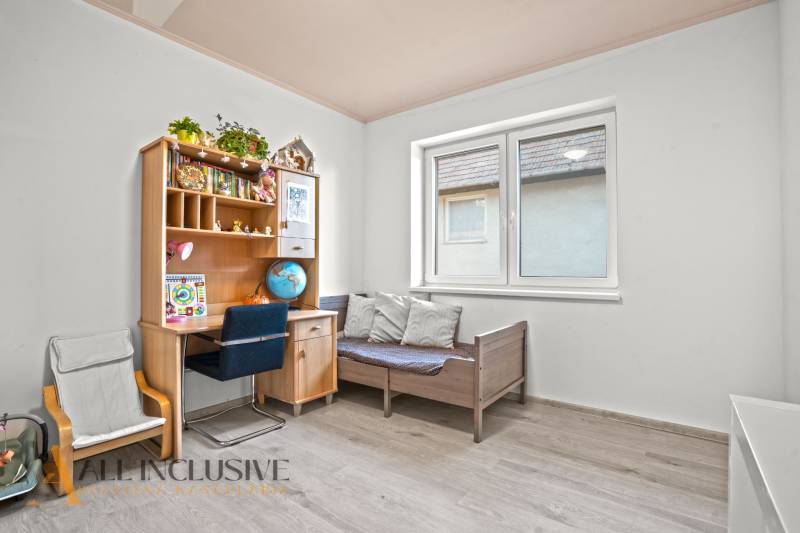 REZERVOVANÉ 5-IZBOVÝ RODINNÝ DOM VO VEĽKEJ PAKE - Detská izba s kreslom, posteľou a stolom v rodinnom dome, podlaha s dreveným dekorom.