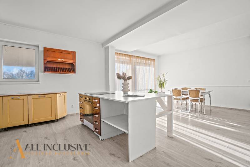 REZERVOVANÉ 5-IZBOVÝ RODINNÝ DOM VO VEĽKEJ PAKE - Kuchyňa v rodinnom dome s podlahou s dreveným dekorom, svetlým nábytkom a veľkým oknom.