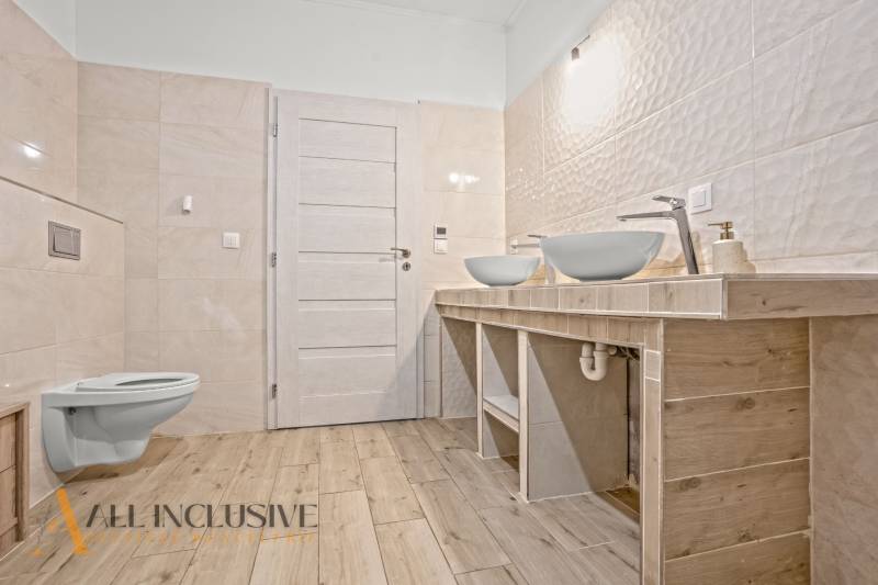 REZERVOVANÉ 5-IZBOVÝ RODINNÝ DOM VO VEĽKEJ PAKE - Kúpeľňa v rodinnom dome s dvoma umývadlami, svetlé obklady, podlaha s dreveným dekorom.