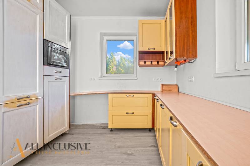 REZERVOVANÉ 5-IZBOVÝ RODINNÝ DOM VO VEĽKEJ PAKE - Kuchyňa v rodinnom dome s podlahou s dreveným dekorom a žltými skrinkami.