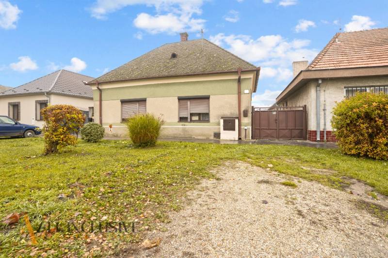 NA PREDAJ 4-IZBOVÝ RODINNÝ DOM V OBCI MOSTOVÁ - Rodinný dom v Mostovej so zelenou fasádou a záhradou s kríkmi.