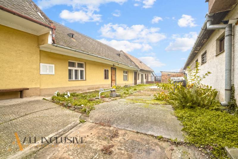 NA PREDAJ 4-IZBOVÝ RODINNÝ DOM V OBCI MOSTOVÁ - Rodinný dom v Mostovej s tradičnou žltou fasádou a zeleným dvorom.