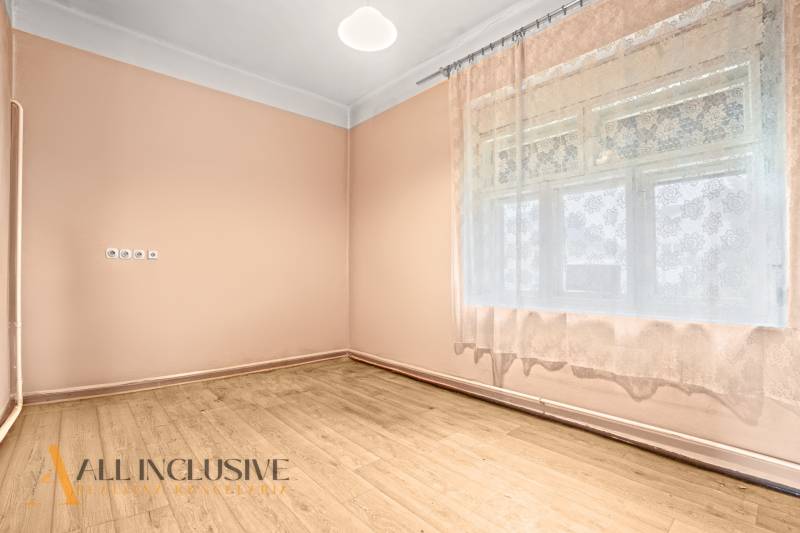 NA PREDAJ 4-IZBOVÝ RODINNÝ DOM V OBCI MOSTOVÁ - Izba s podlahou s dreveným dekorom a záclonami v rodinnom dome.