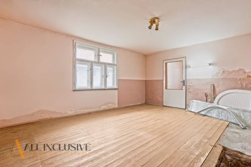 NA PREDAJ 4-IZBOVÝ RODINNÝ DOM V OBCI MOSTOVÁ - Opustená miestnosť v rodinnom dome s podlahou s dreveným dekorom a oprýskanou omietkou.