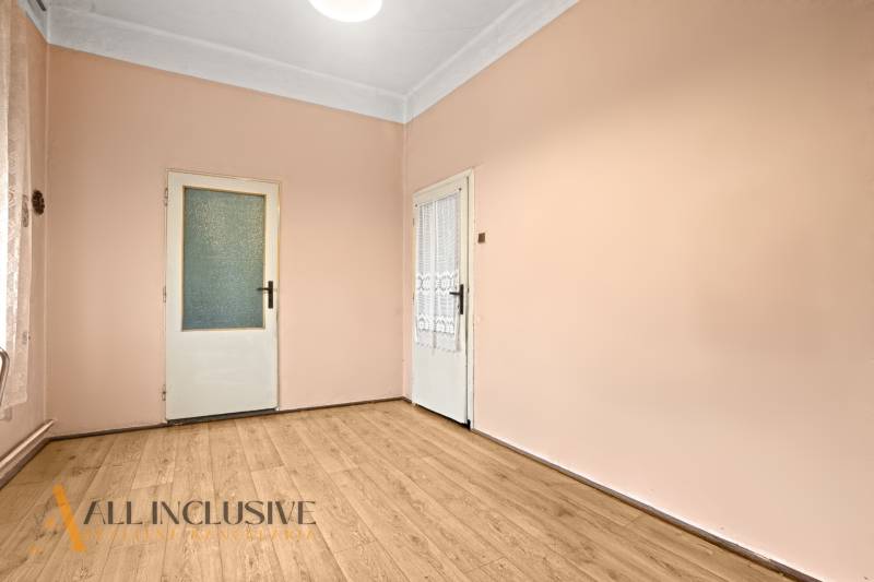 NA PREDAJ 4-IZBOVÝ RODINNÝ DOM V OBCI MOSTOVÁ - Izba so svetlými stenami, podlahou s dreveným dekorom a dvomi bielymi dverami v Rodinnom dome.