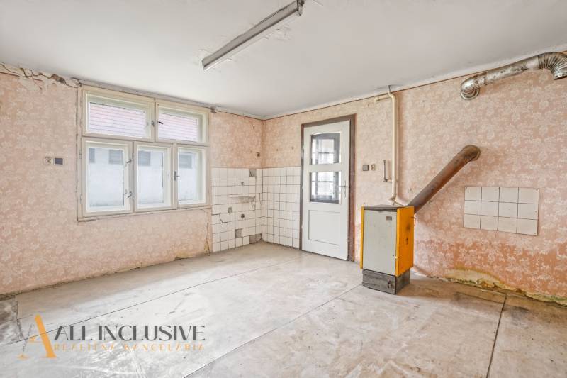 NA PREDAJ 4-IZBOVÝ RODINNÝ DOM V OBCI MOSTOVÁ - Prázdna miestnosť s oknom a dverami v rodinnom dome, jednoducho zariadená.