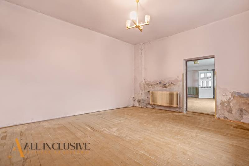 NA PREDAJ 4-IZBOVÝ RODINNÝ DOM V OBCI MOSTOVÁ - Izba v rodinnom dome s radiátorom a podlahou s dreveným dekorom, potrebujúca renováciu.