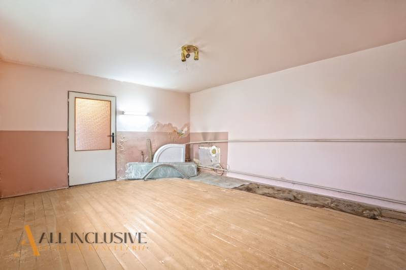 NA PREDAJ 4-IZBOVÝ RODINNÝ DOM V OBCI MOSTOVÁ - Interiér rodinného domu s podlahou s dreveným dekorom a poškodenou stenou.