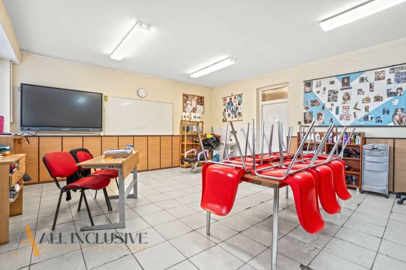 NA PREDAJ ŠKOLSKÁ BUDOVA NA VEĽKOM POZEMKU, MOSTOVÁ - Interiér učebne s červenými stoličkami, školská tabuľa a nástenky na stenách.