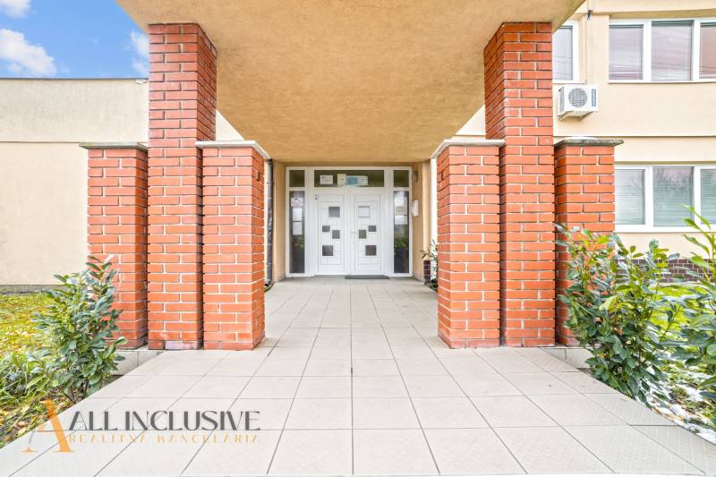 NA PREDAJ ŠKOLSKÁ BUDOVA NA VEĽKOM POZEMKU, MOSTOVÁ - Vchod do budovy v Mostovej, s tehlovými stĺpmi, dlažbou a rastlinami.