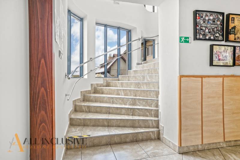 NA PREDAJ ŠKOLSKÁ BUDOVA NA VEĽKOM POZEMKU, MOSTOVÁ - Schodisko s dlaždicovou podlahou v budove, steny so zábradlím a obrazmi.