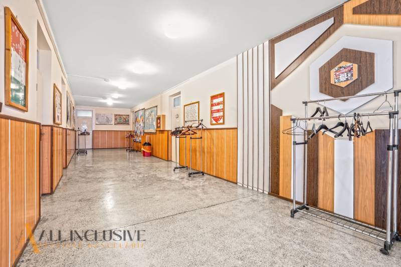 NA PREDAJ ŠKOLSKÁ BUDOVA NA VEĽKOM POZEMKU, MOSTOVÁ - Interiér budovy so stenami z dreveného dekoru a vešiakmi na kabáty.