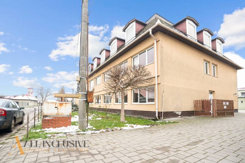 NA PREDAJ ŠKOLSKÁ BUDOVA NA VEĽKOM POZEMKU, MOSTOVÁ - Budova v Mostovej s modernými architektonickými prvkami a parkoviskom na ulici.