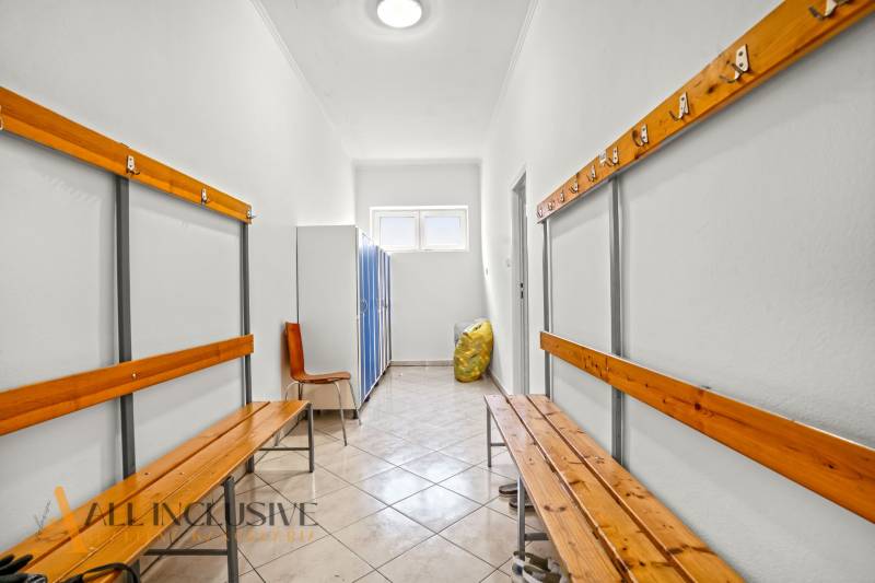 NA PREDAJ ŠKOLSKÁ BUDOVA NA VEĽKOM POZEMKU, MOSTOVÁ - Šatňa v budove s drevenými lavicami, skriňami a dlažbou.